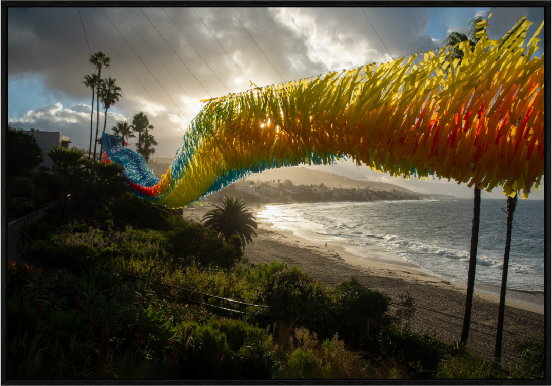 Colorful fabric sculpture on a beach with palm trees and ocean view